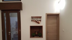 Une pièce avec une porte en bois, une petite étagère avec des plantes et un banc rouge.