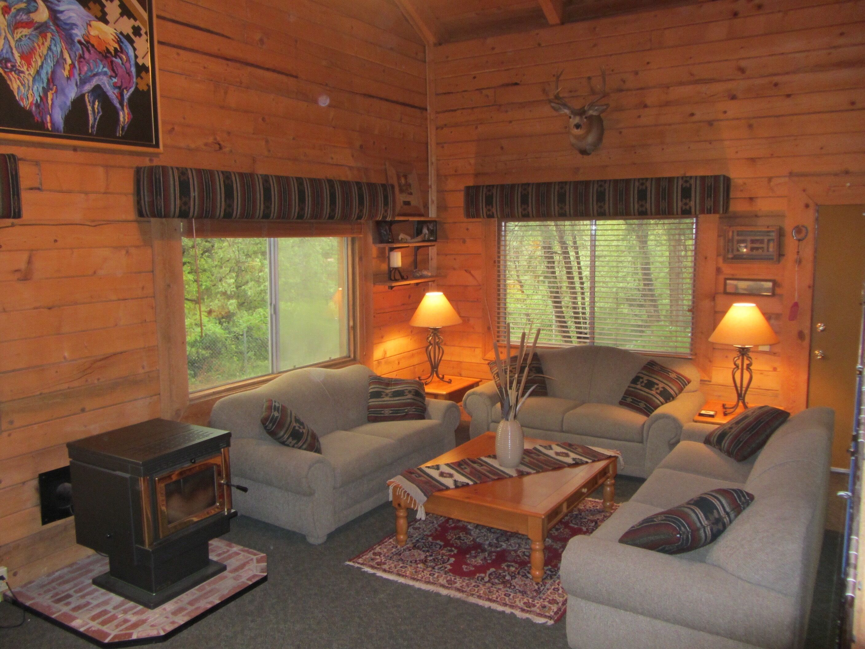 A cozy cabin interior with a fireplace, two sofas, a coffee table, and two lamps.