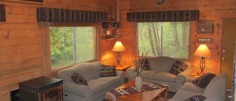 A cozy cabin interior with a fireplace, two sofas, a coffee table, and two lamps.