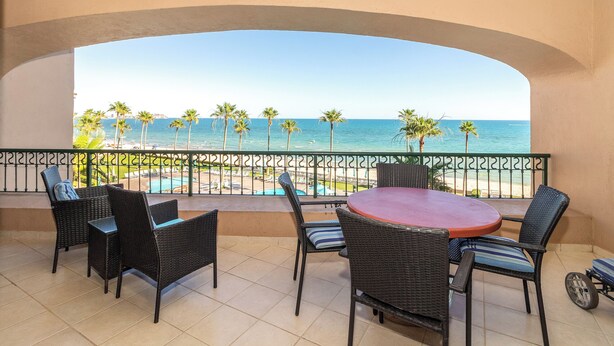 A balcony with wicker furniture and a view of the sea.
