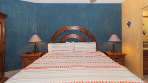 A bedroom with a wooden headboard, two bedside tables with lamps, and a bed with striped bedding.