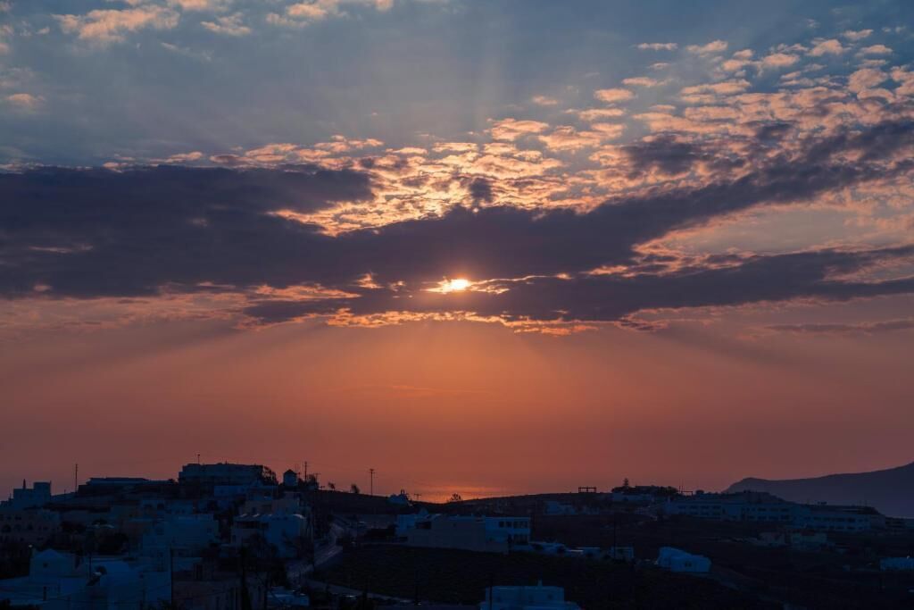 A coastal cityscape at sunset with buildings silhouetted against the sky.