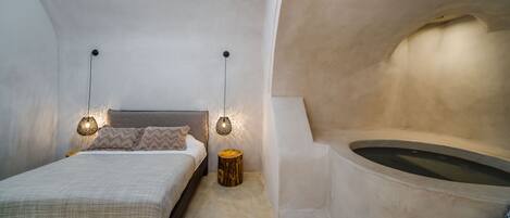 A bedroom with a bed, bedside lamps, and a bathtub.