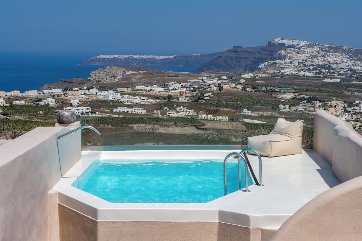Une piscine sur le toit offrant une vue dégagée sur une ville côtière et une montagne en arrière-plan.