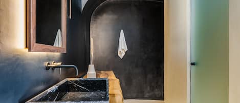 Een moderne badkamer met een marmeren wastafel, een houten opbergmeubel en een grote spiegel.