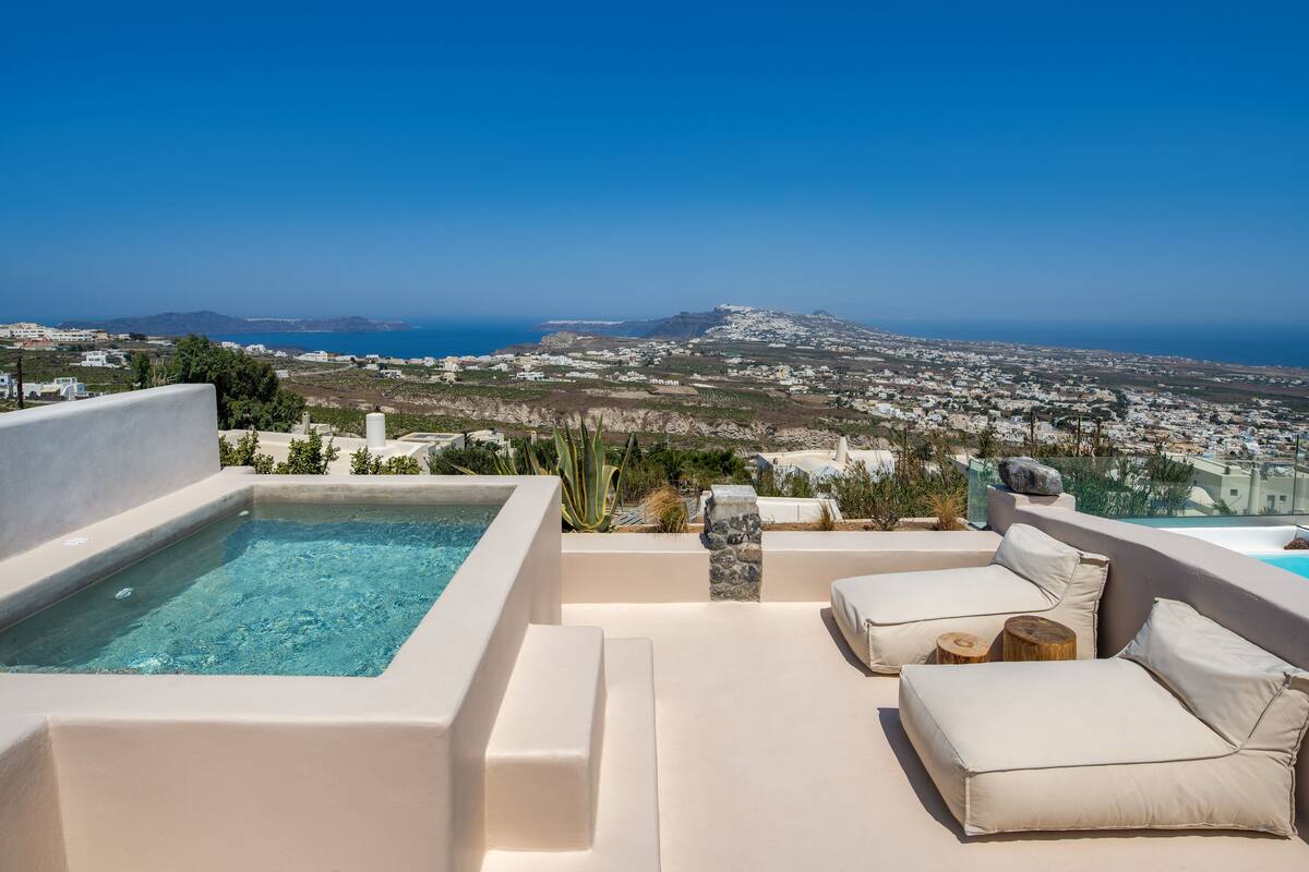 Une terrasse sur le toit avec une piscine, des espaces de détente en plein air et une vue sur une ville côtière et les montagnes.