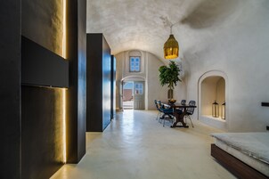 Una habitación amplia con zona de comedor, cama y lámpara colgante.
