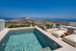 Une piscine à débordement située sur le toit, offrant une vue sur une ville côtière et une montagne au loin.