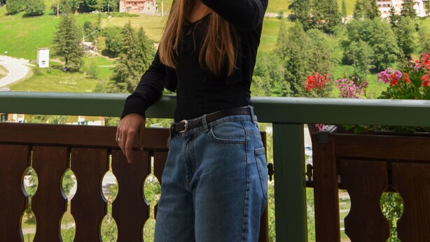 Un balcon donnant sur une vallée verdoyante et des montagnes.
