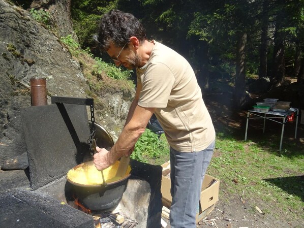 A person cooking outdoors using a portable stove. - Zanella (Pejo)