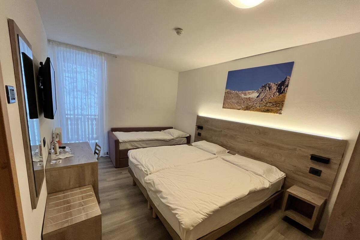 A hotel room with two beds, a desk, and a mirror.