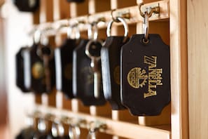 A row of black keychains with the text "Hotel Zanella" hanging on a wooden rack. - Zanella (Pejo)