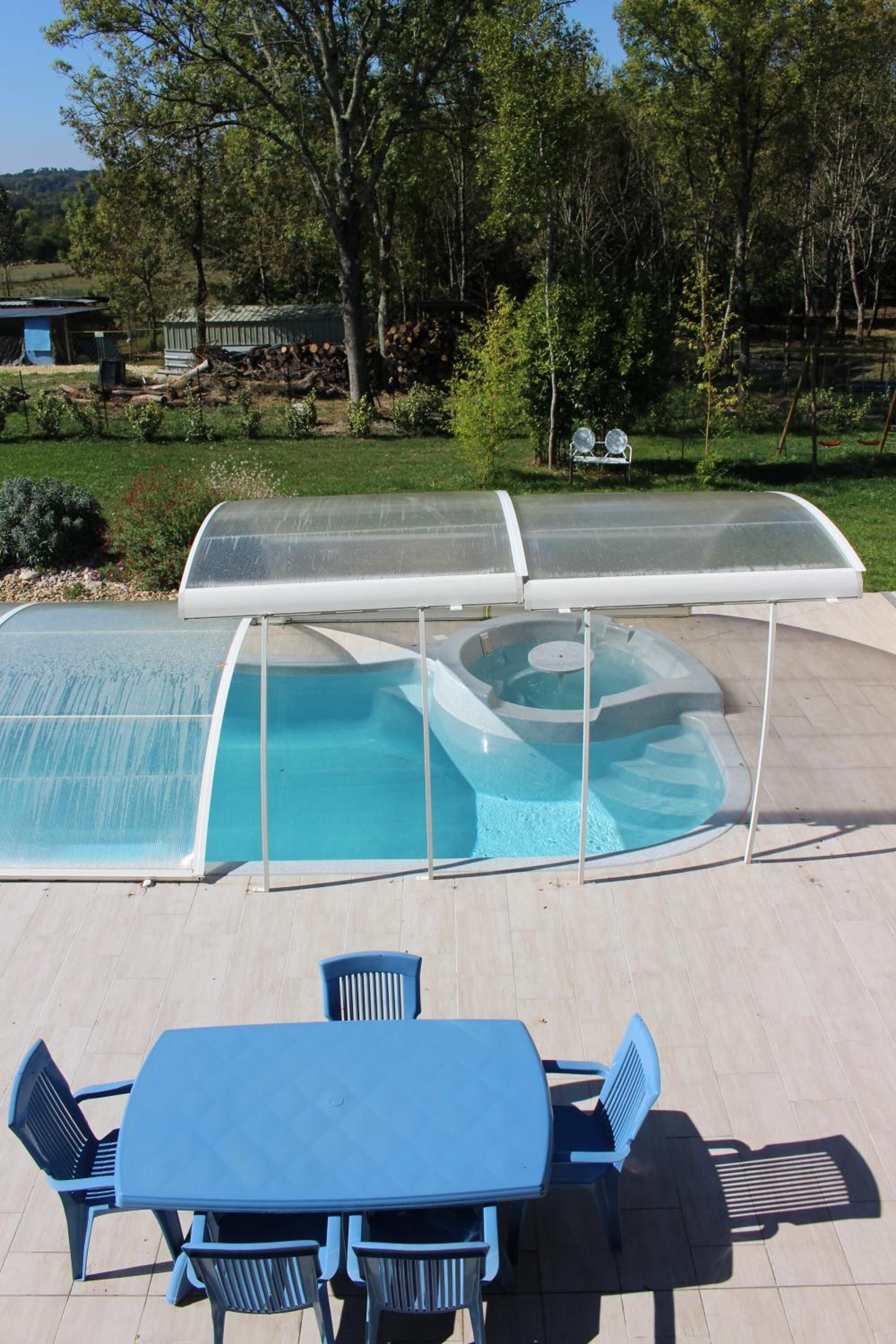 A covered outdoor swimming pool with a table and chairs in front.