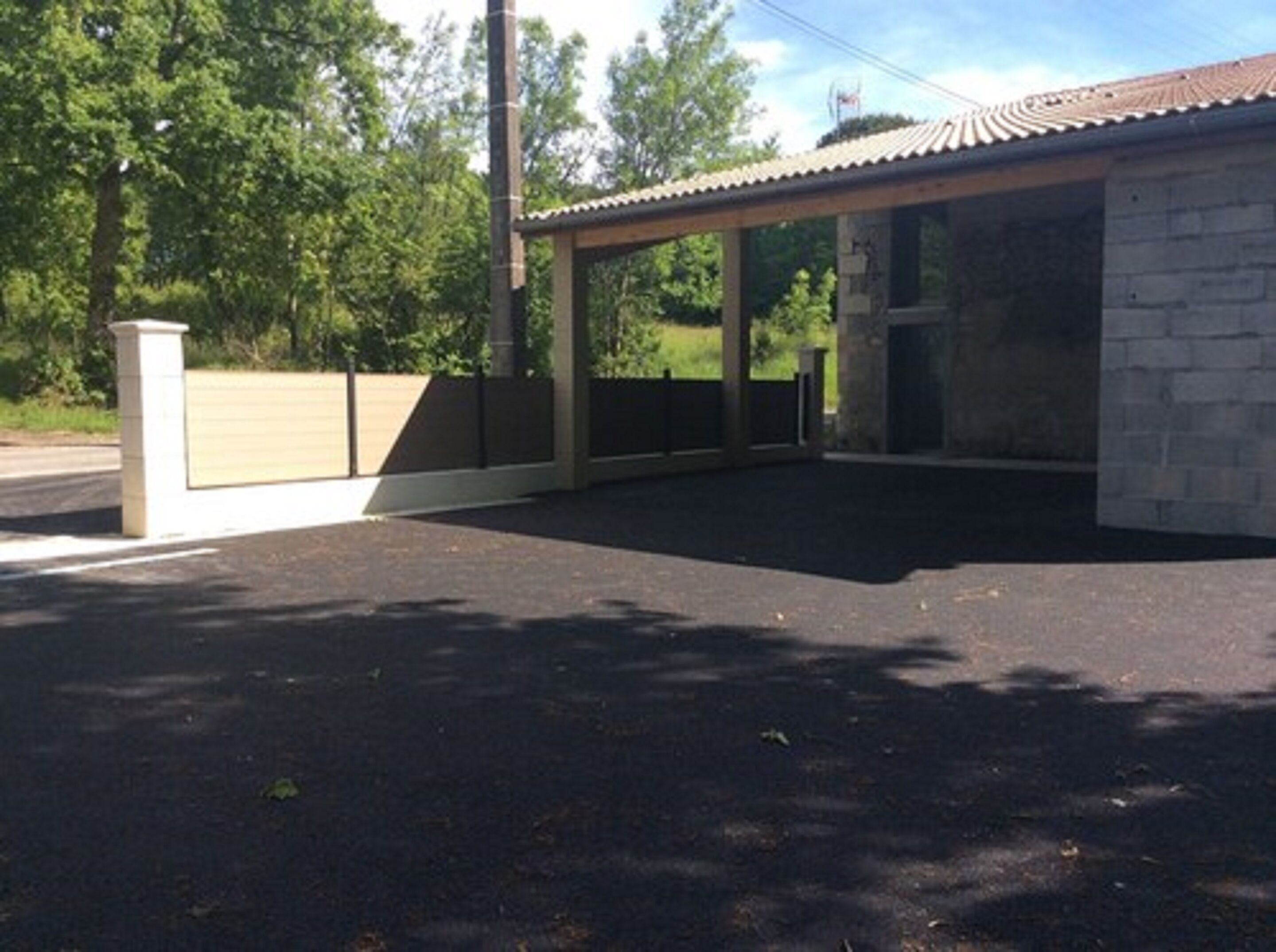 Un espace extérieur abrité, doté d’un mur en pierre, d’une clôture en métal et d’un sol pavé.