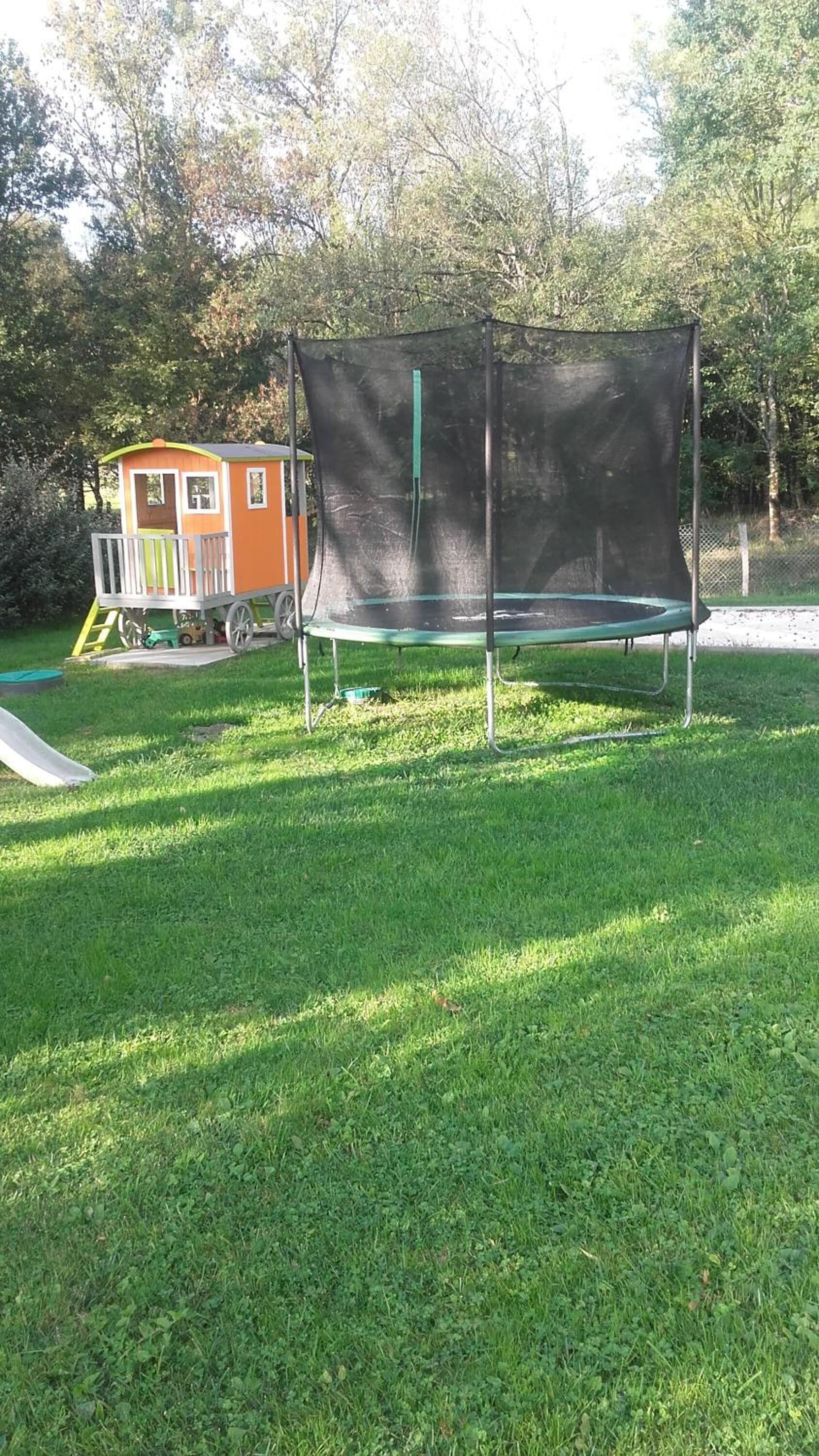 A trampoline with a safety net in a grassy area.