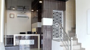 A modern reception area with a reception desk, a staircase, and a ceiling fan. - Hotel Metro View (Jaipur)