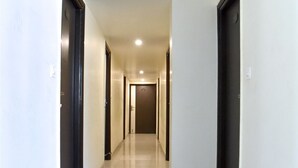 A long, narrow hallway with white walls and a tiled floor. - Hotel Metro View (Jaipur)