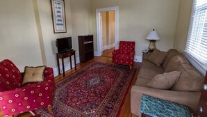 A living room with a sofa, armchair, TV, and a patterned rug. - Classic Uptown Shotgun, Just Steps to the Streetcar ! (New Orleans)