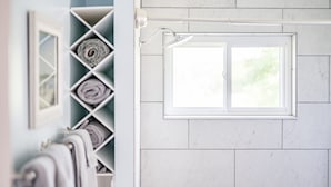 Un bagno con doccia, una finestra e un porta asciugamani con asciugamani.