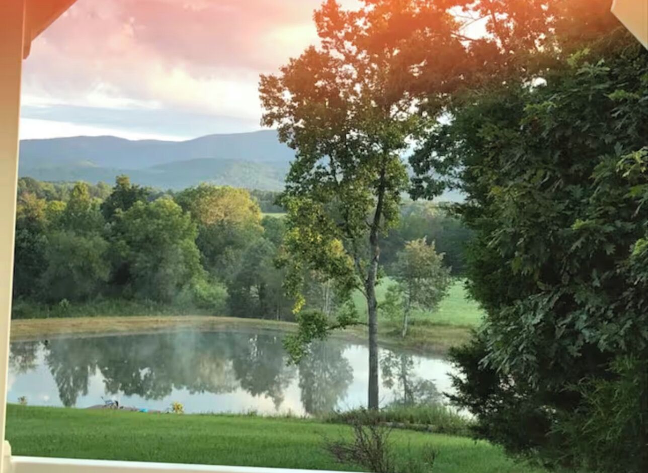 A serene landscape with a lake, trees, and distant mountains.