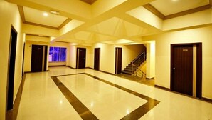 Un vestíbulo amplio con un área central abierta, una escalera y varias puertas que dan a las habitaciones.
