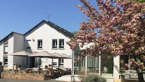 Un bâtiment doté d’un patio, d’un espace extérieur aménagé pour s’asseoir et d’un arbre aux fleurs roses.