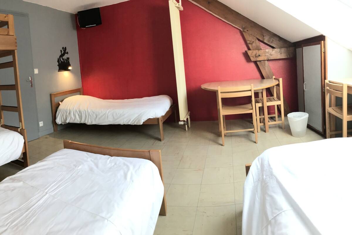 Een slaapzaal met stapelbedden, een bureau en een stoel.