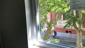 Una ventana con vista a un árbol y un edificio.