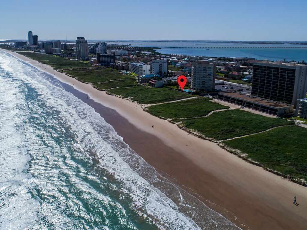 Une vue aérienne d’une ville côtière, avec une plage, des bâtiments et un pont au loin.