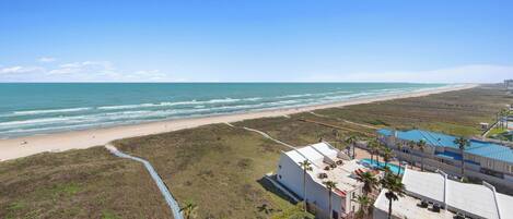A coastal property with a beach view, a swimming pool, and a small garden.