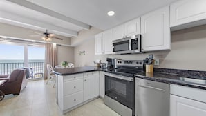 Une cuisine moderne dotée d’appareils électroménagers en acier inoxydable, de meubles blancs et d’un grand îlot central.