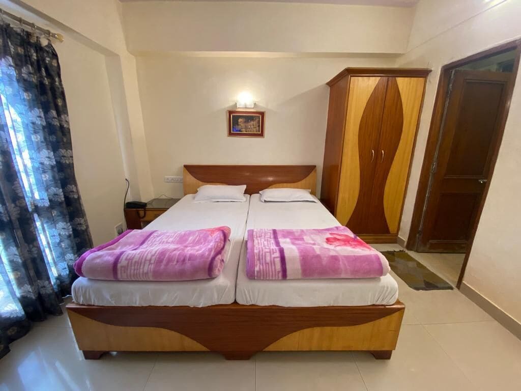 Un lit double avec deux oreillers et une couverture, une armoire en bois et une porte.