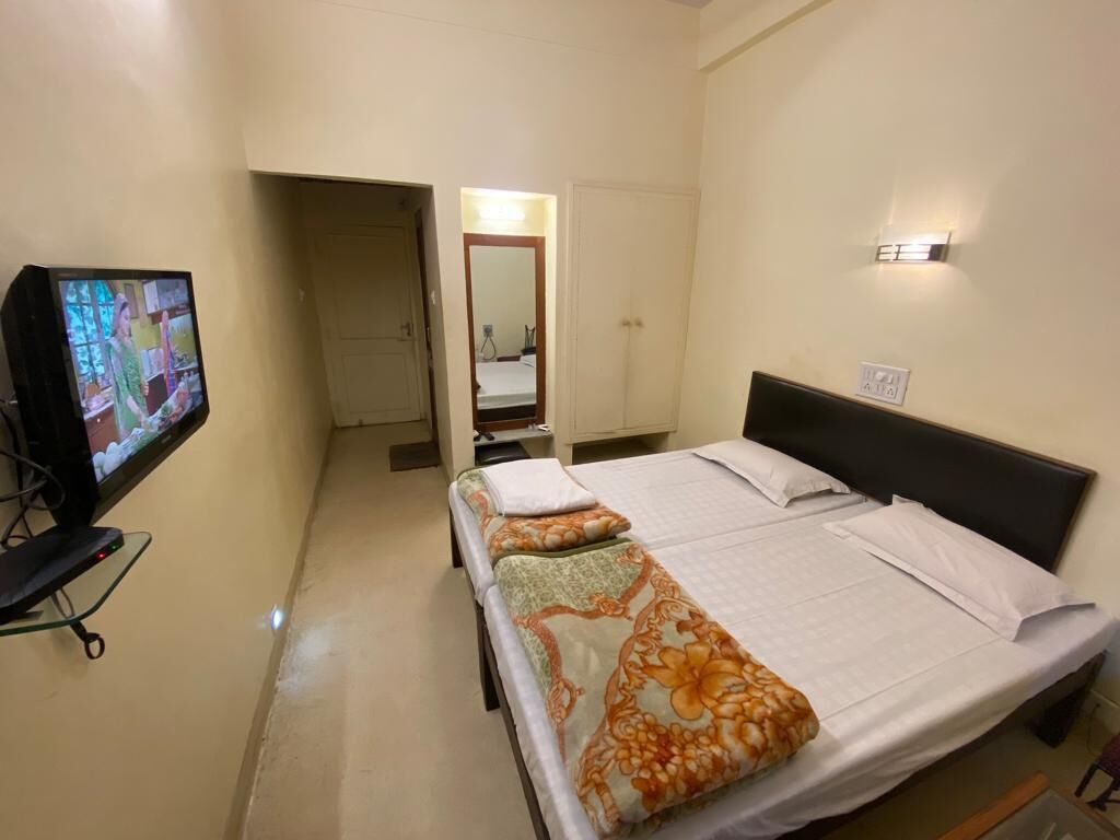 Una habitación de hotel con una cama, un televisor y un espejo.