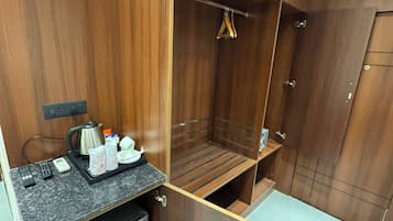A compact room with a built-in kitchenette, a wardrobe, and a seating area.