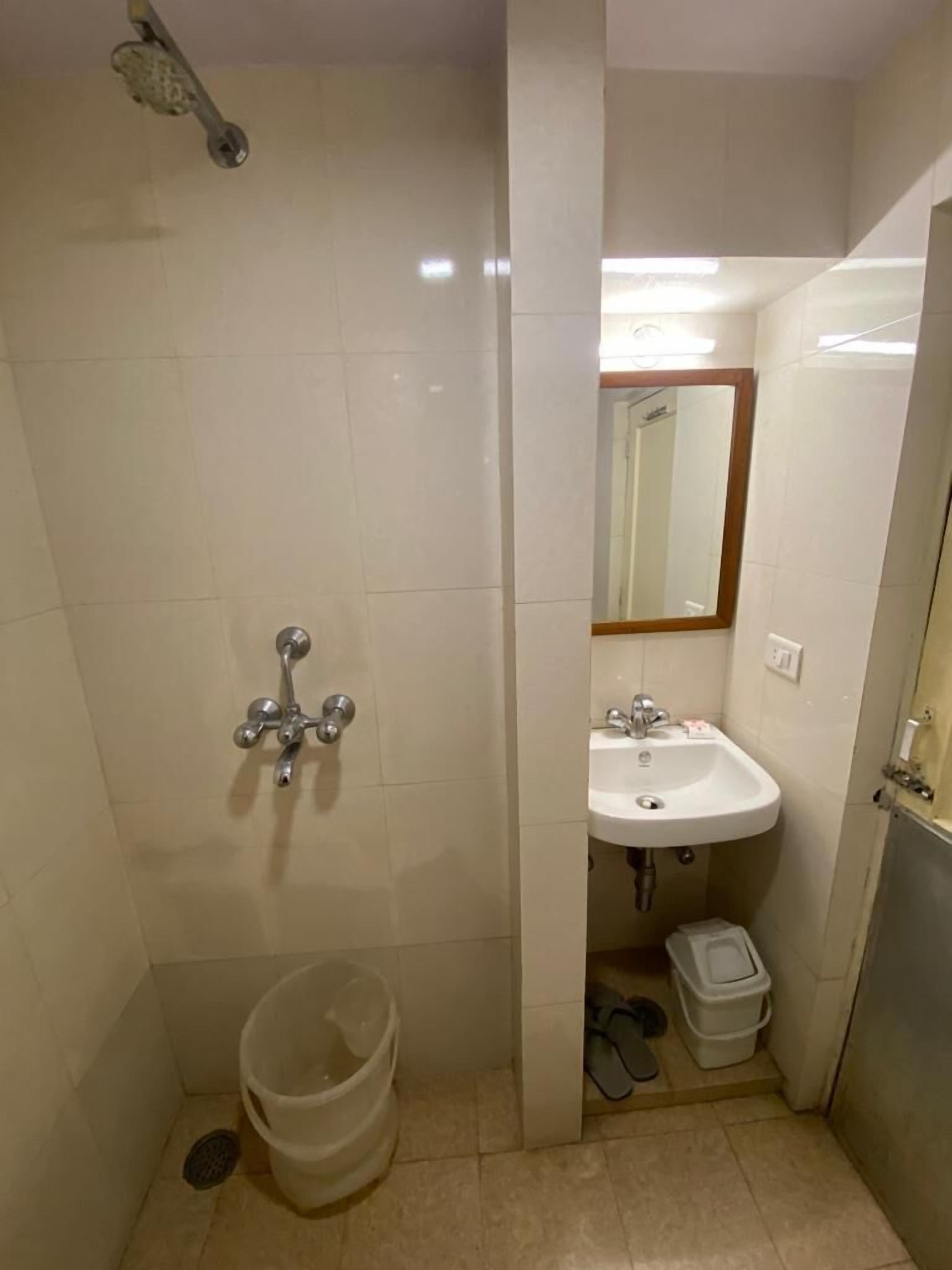 Un baño pequeño con ducha, lavamanos y espejo.