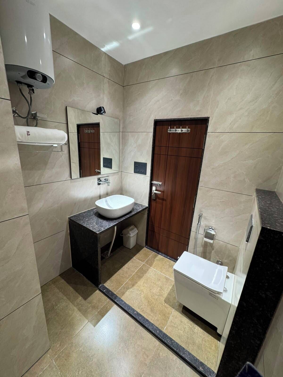 Un baño pequeño con lavamanos, espejo, toallero y zona de ducha.