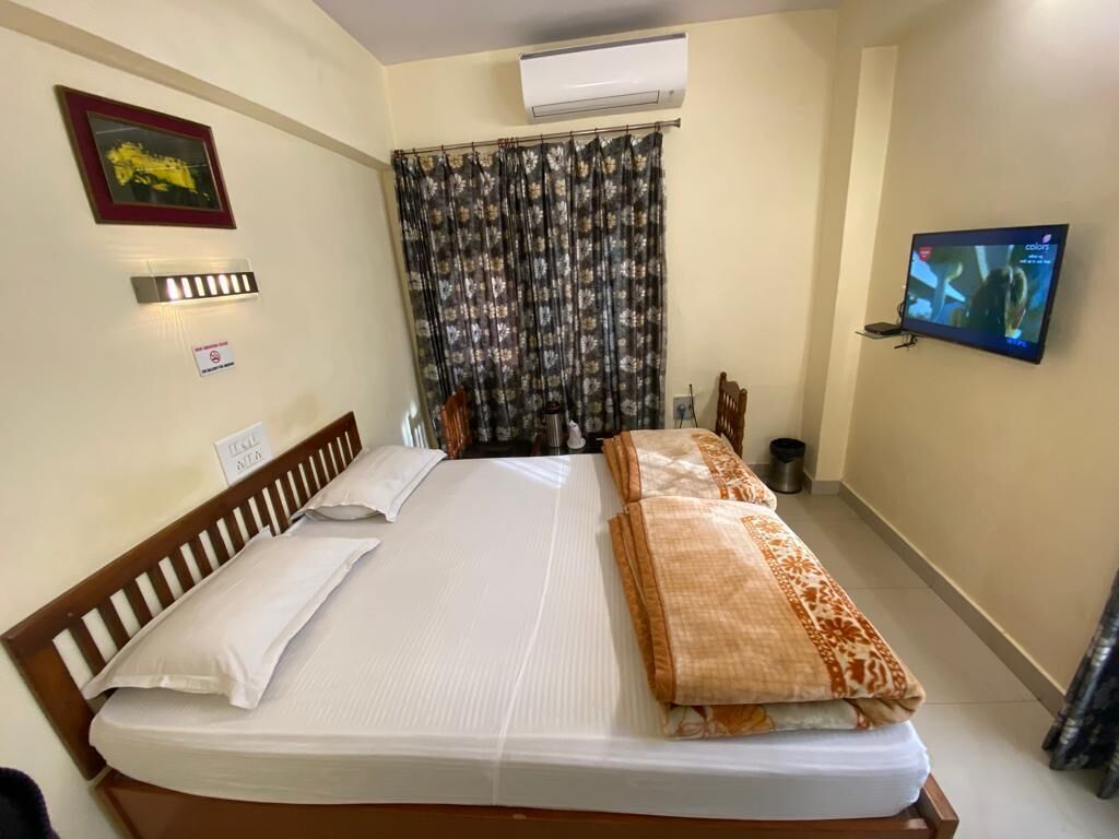 Une chambre d’hôtel équipée d’un lit, d’une télévision, d’un rideau et d’un climatiseur fixé au mur.