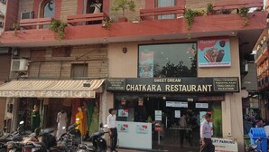 Un edificio de varios pisos con un restaurante llamado 'Sweet Dream Chatkara Restaurant' en la planta baja.