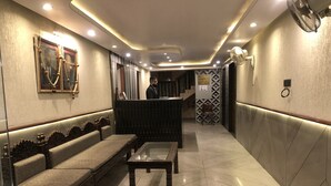 Un vestíbulo de hotel con mostrador de recepción, zona de estar y pared con diseño.
