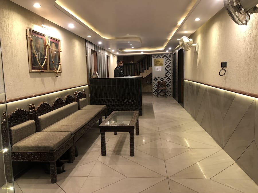 Un vestíbulo de hotel con mostrador de recepción, zona de estar y pared con diseño.