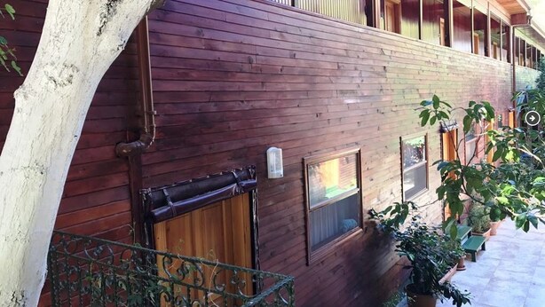 A wooden building with a balcony, potted plants, and a tree. - Divasa Hotel (Kumluca)