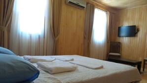 A hotel room with a bed, a flat-screen TV mounted on the wall, and a window with curtains. - Divasa Hotel (Kumluca)