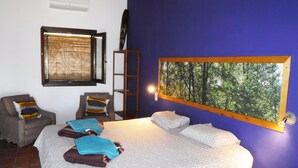 Een slaapkamer met een bed, twee stoelen, een ladder, een raam met zonwering, en een aan de muur hangend beeld van een bos.