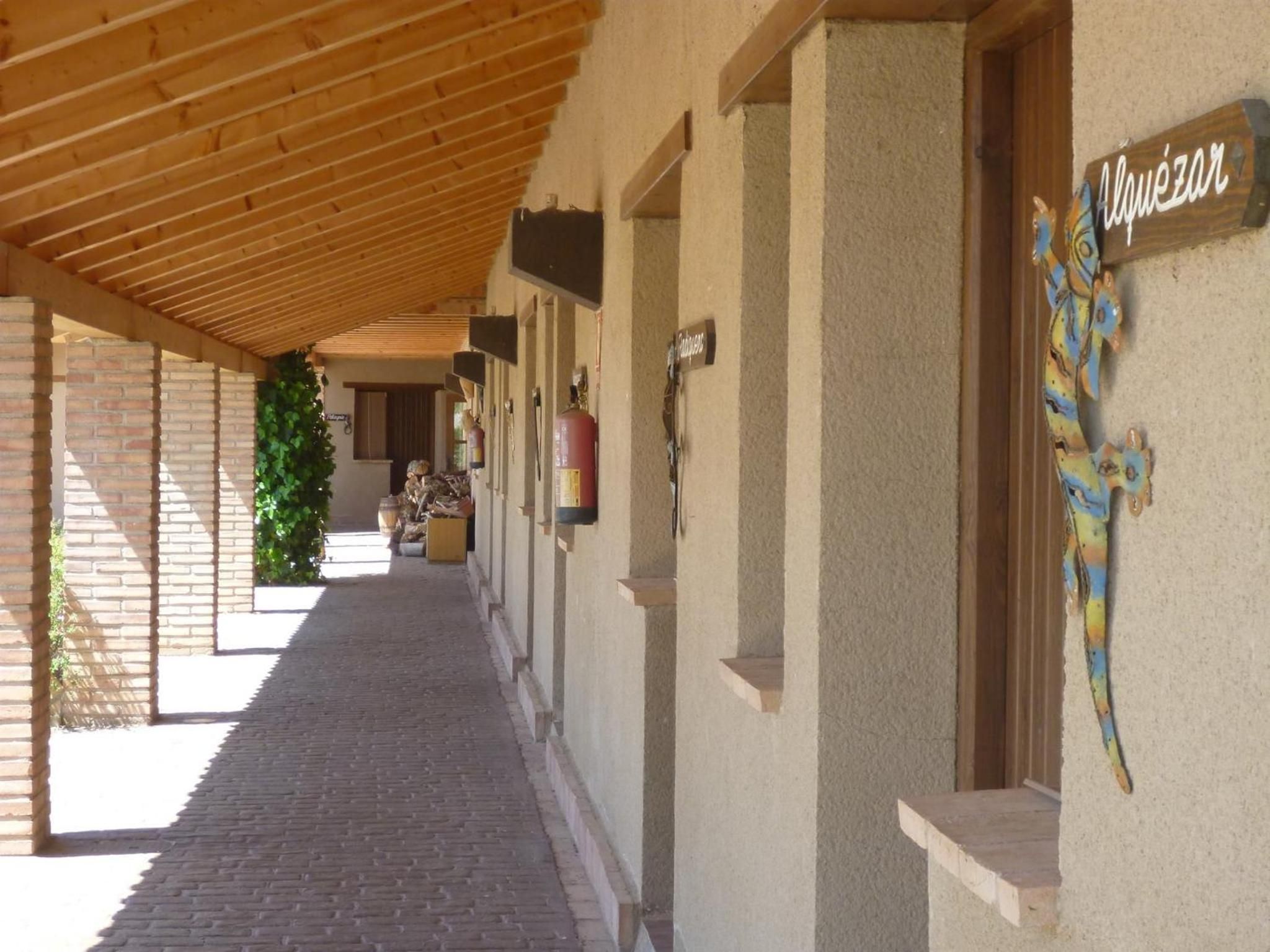 A covered corridor with a brick floor, wooden beams, and a Christmas tree.