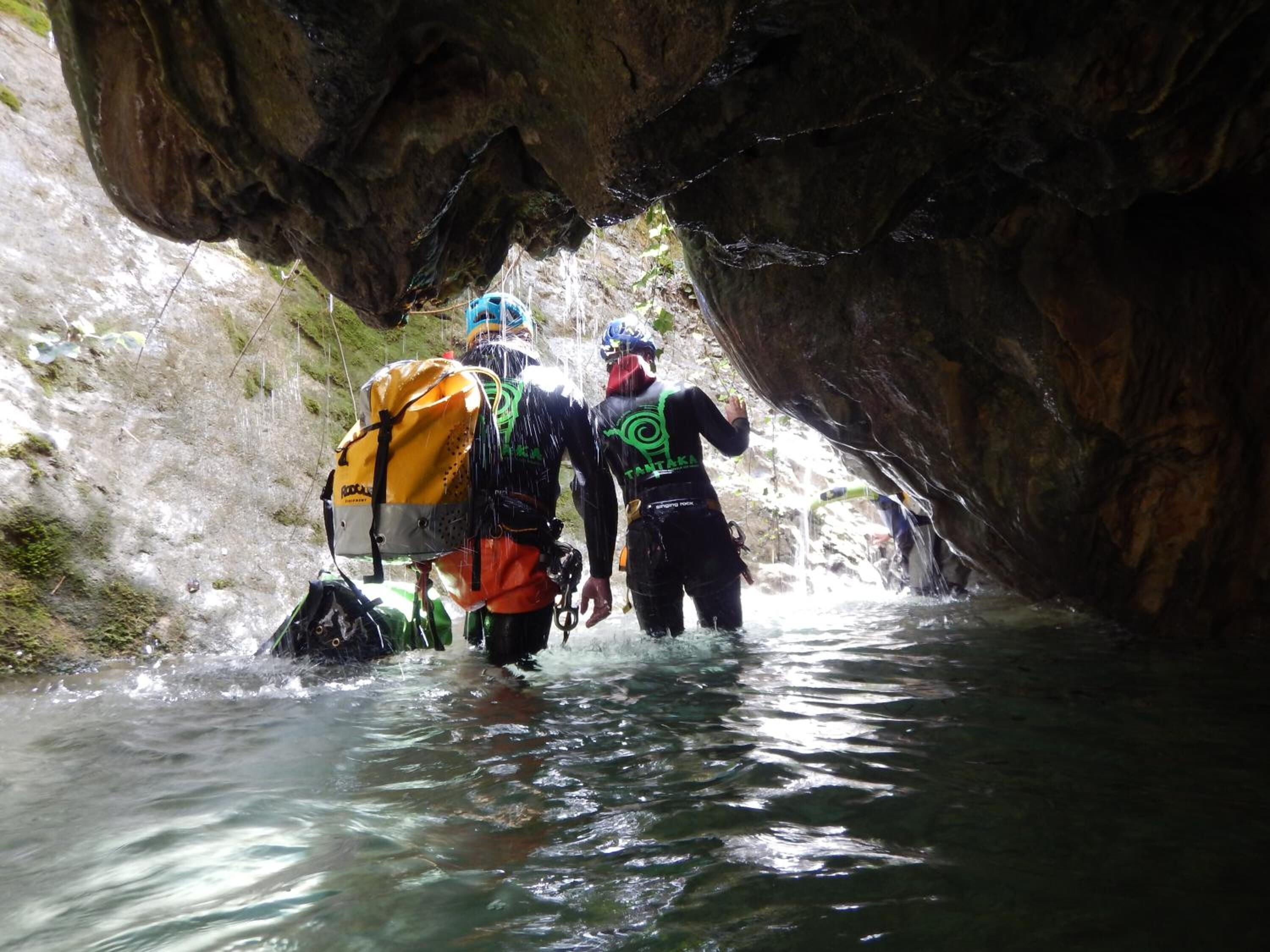 Un grupo de personas caminando por un estrecho canal de agua entre acantilados rocosos.