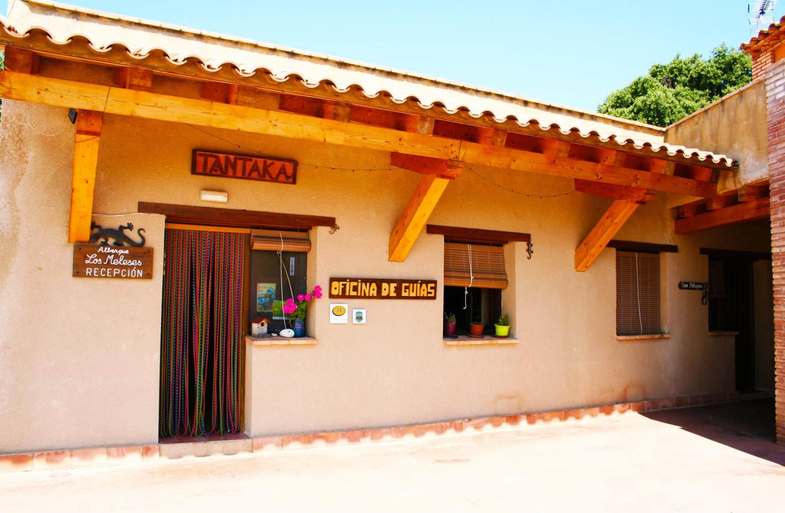 A building with a tiled roof, wooden beams, and signs indicating a reception and office.