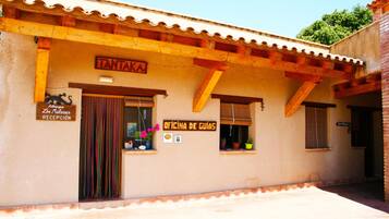 A building with a tiled roof, wooden beams, and signs indicating a reception and office.