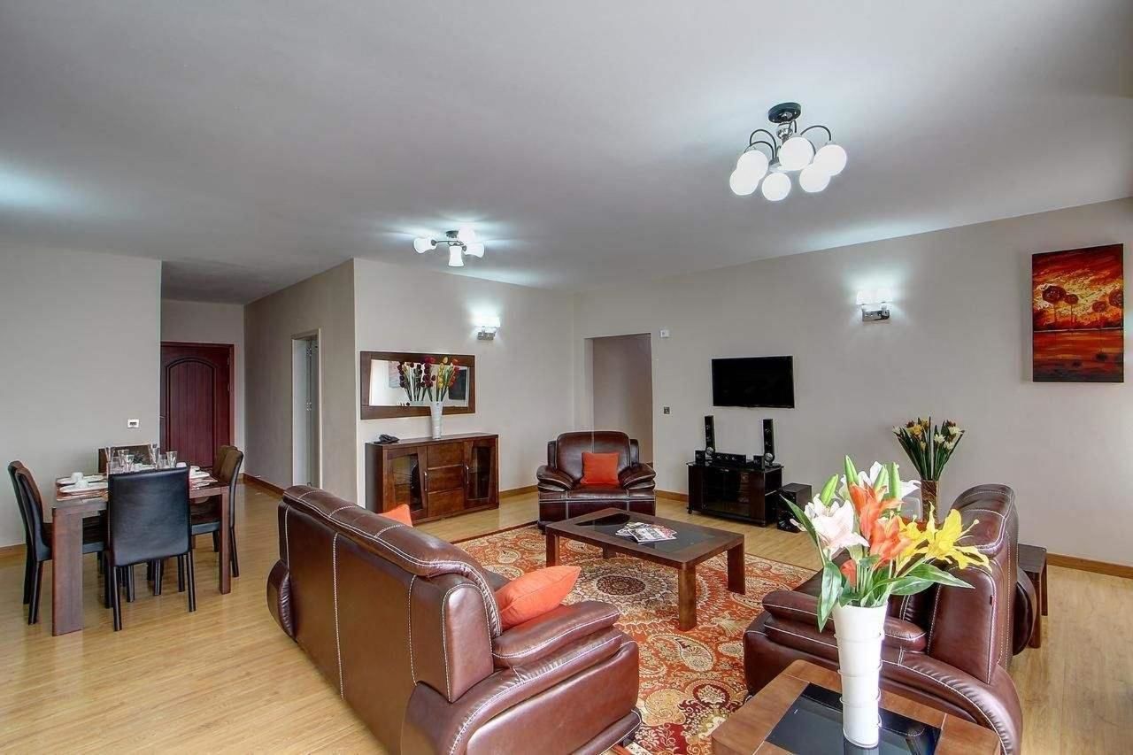 Ein geräumiges Wohnzimmer mit Essbereich, Ledersofas, einem Couchtisch und einem Flachbildfernseher.