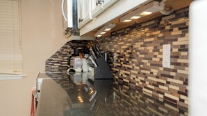 A kitchen with a tiled backsplash, a granite countertop, and modern appliances. - Beachfront, Luxurious, Great Location with Amazing Views!!! (South Padre Island)