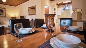 A dining table set with white plates, bowls, and wine glasses, with a decorative vase in the center. - Kilchurn Suites (Dalmally)